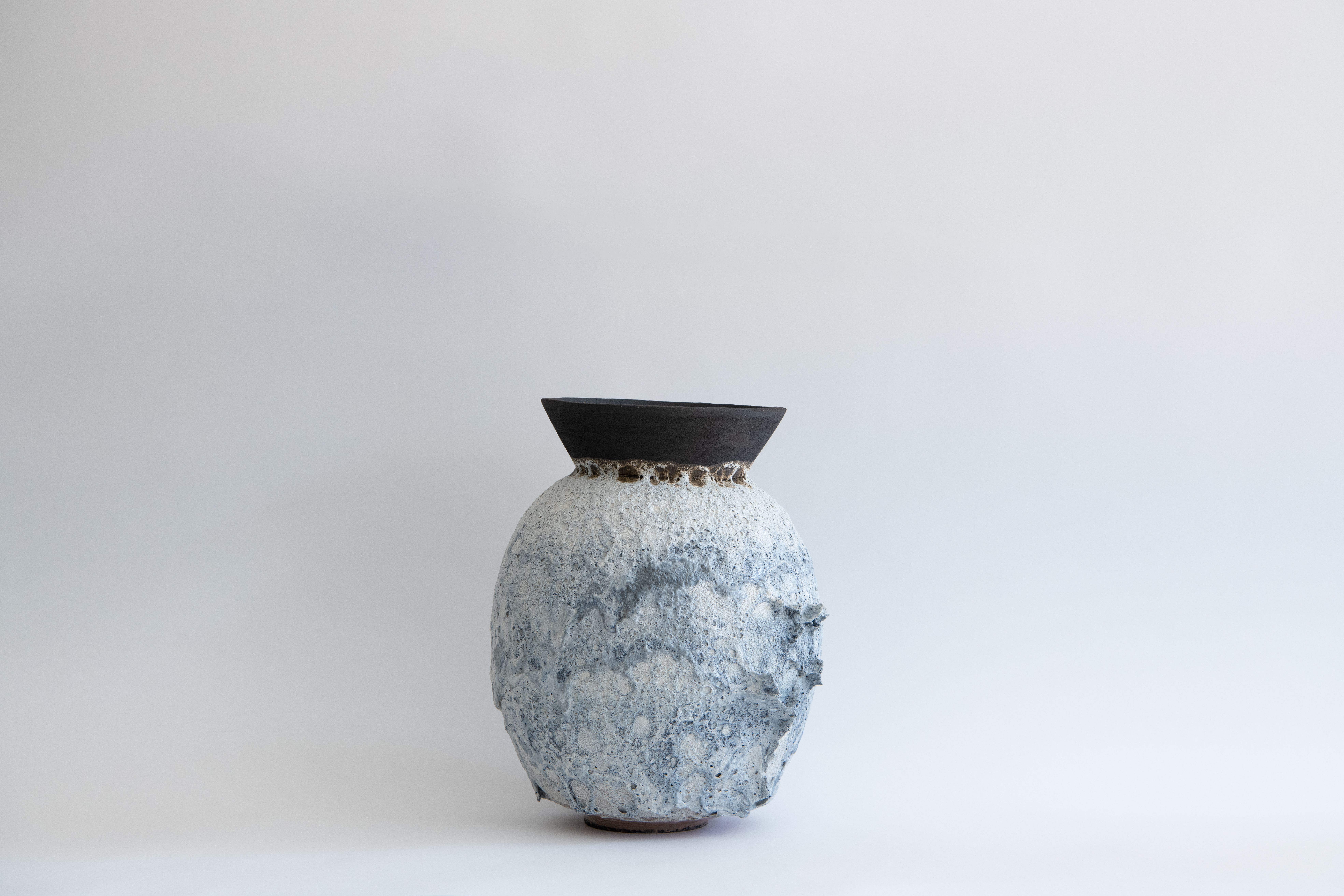Tall pale volcanic Moon Jar with a dark flared rim