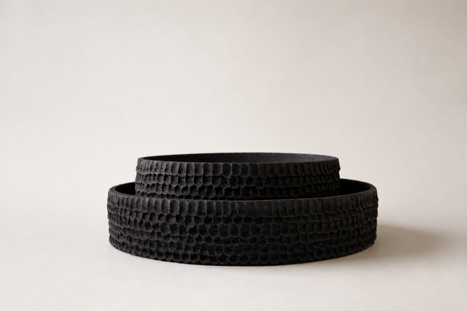 Pair of low black ceramic vessels with deeply textured surfaces