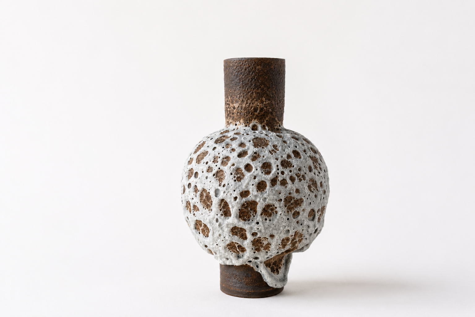 Tall brown ceramic vessel with a white volcanic glaze around its rounded body