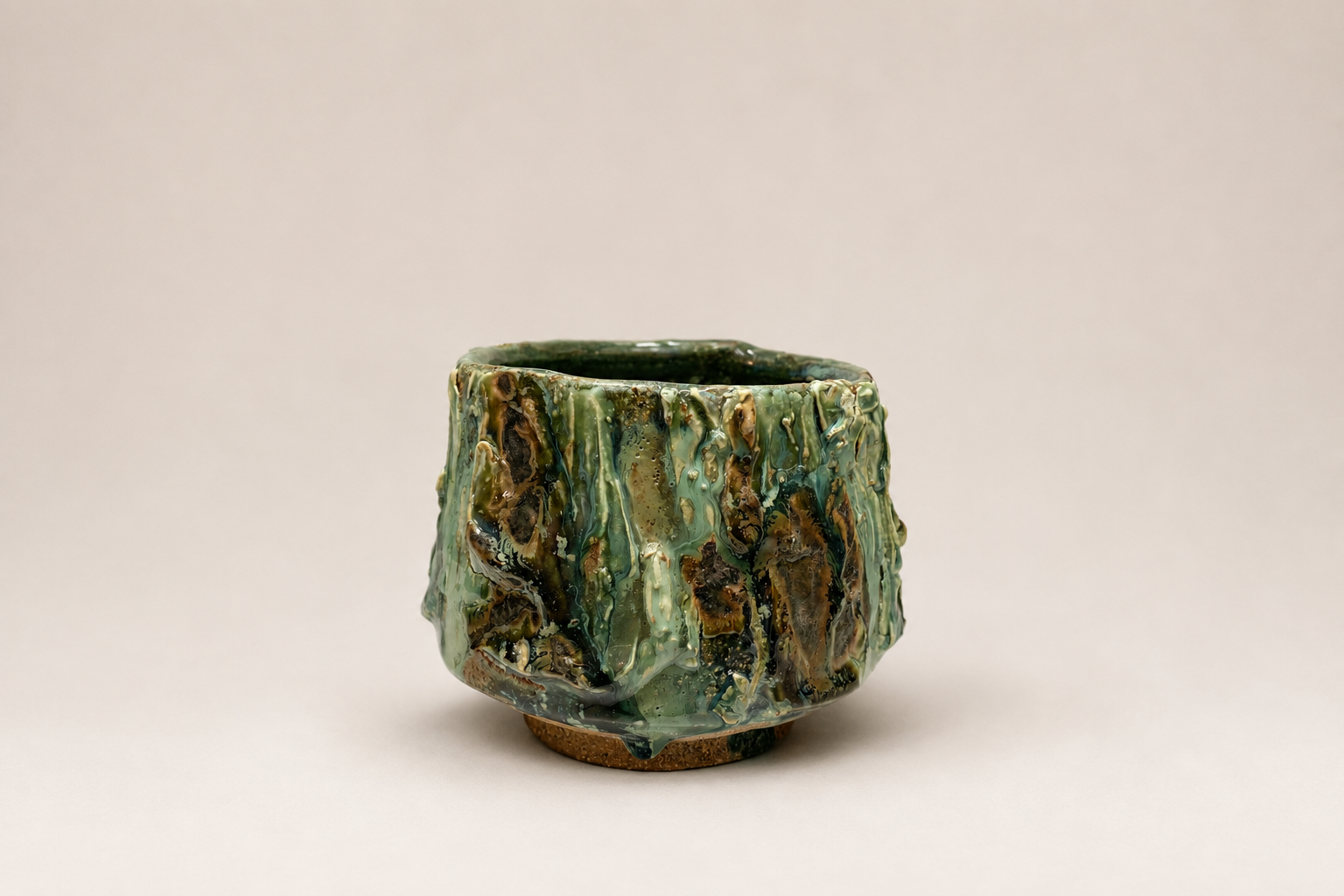 Small green ceramic vessel with a richly layered glossy surface