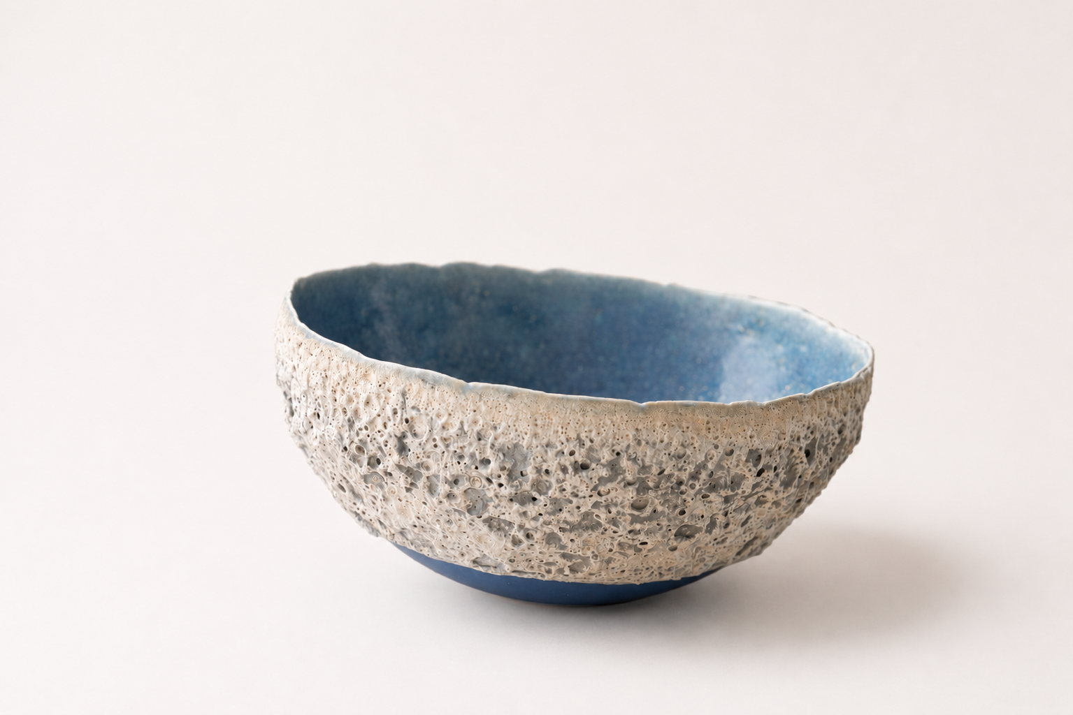 Wide ceramic bowl with a pale volcanic exterior and soft blue interior