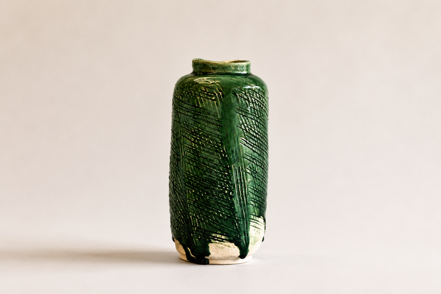 Tall green glazed ceramic vessel with incised geometric decoration