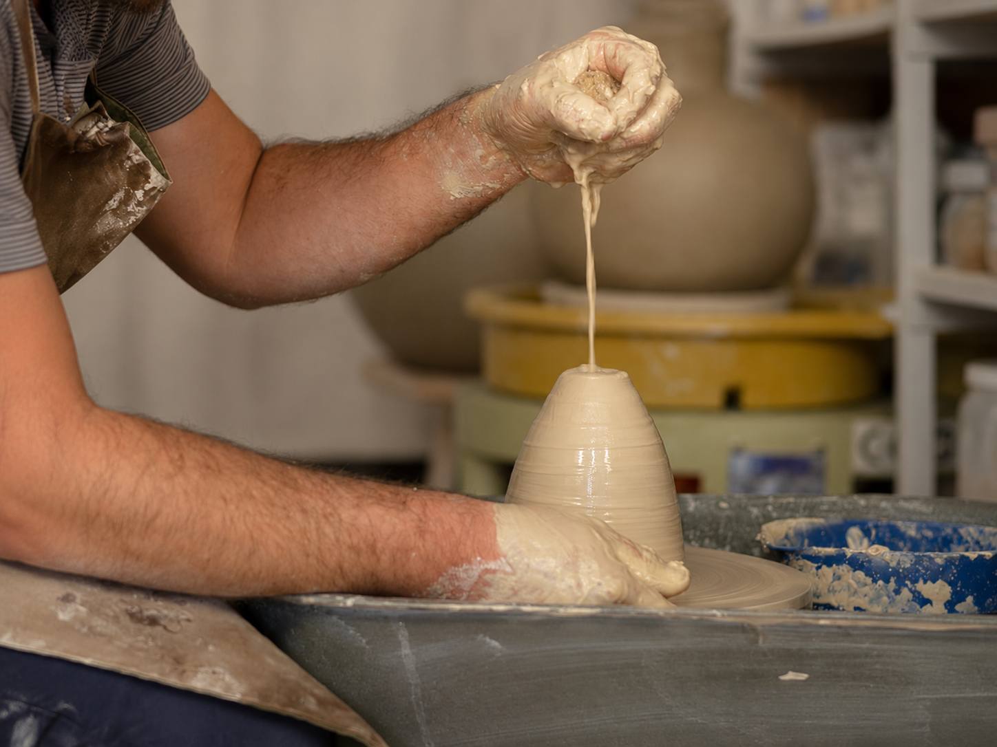 José pulling clay upwards on the pottery wheel