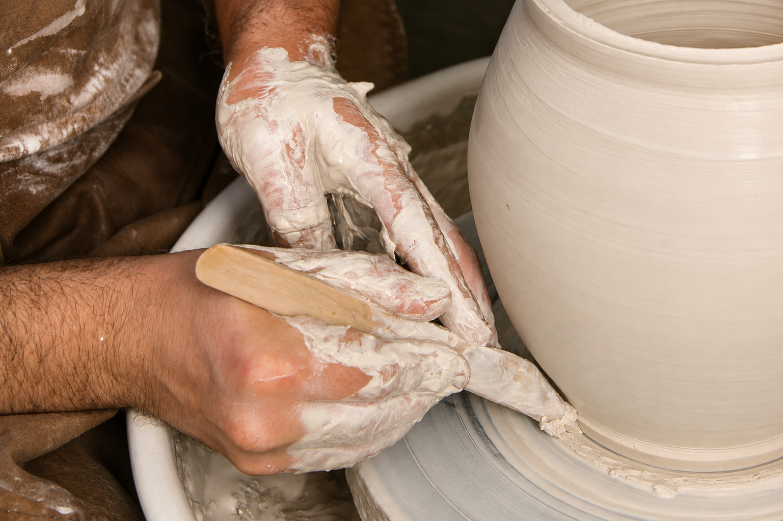 José refining the foot of a ceramic vessel on the wheel