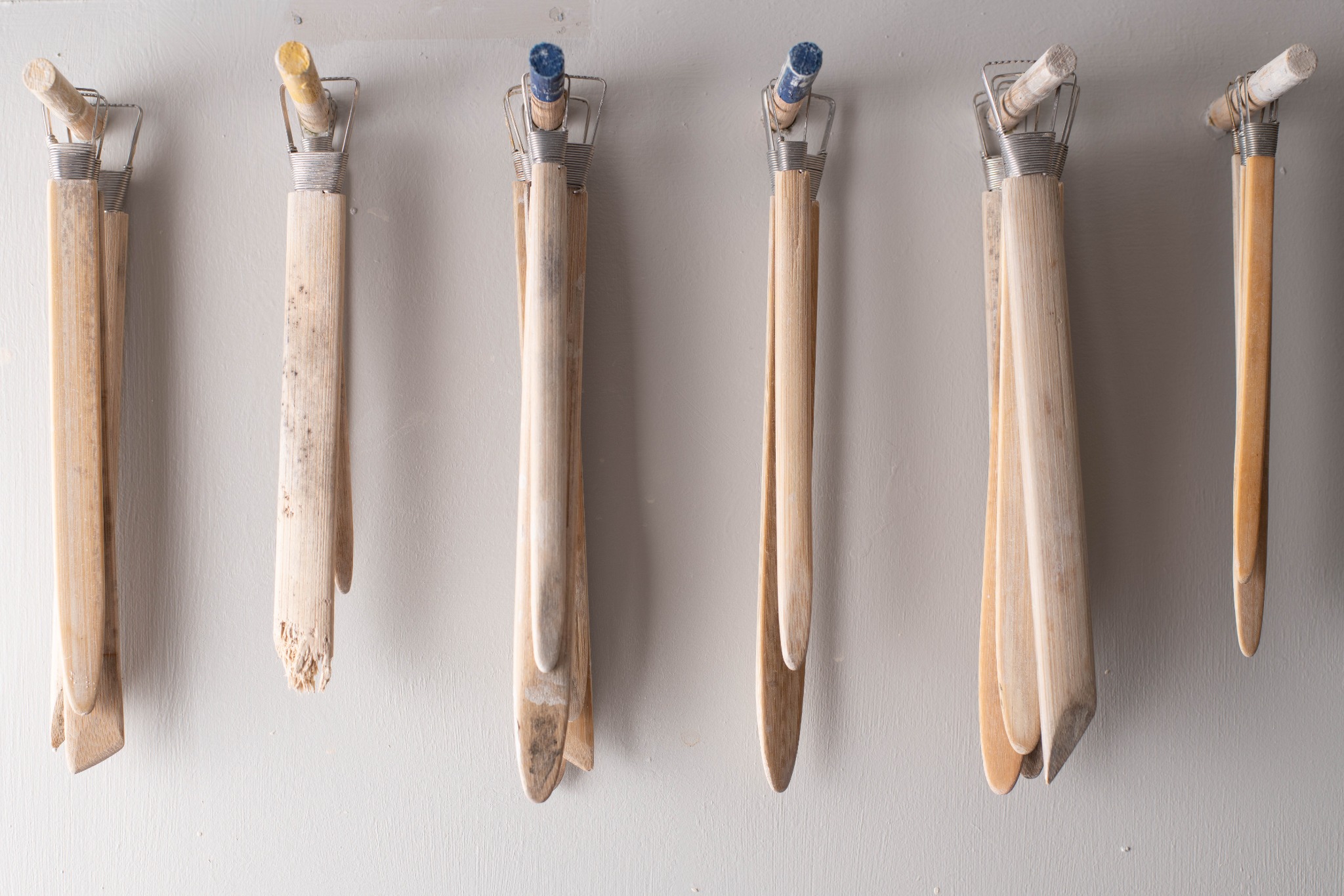 A row of well-used wooden pottery tools on the studio wall