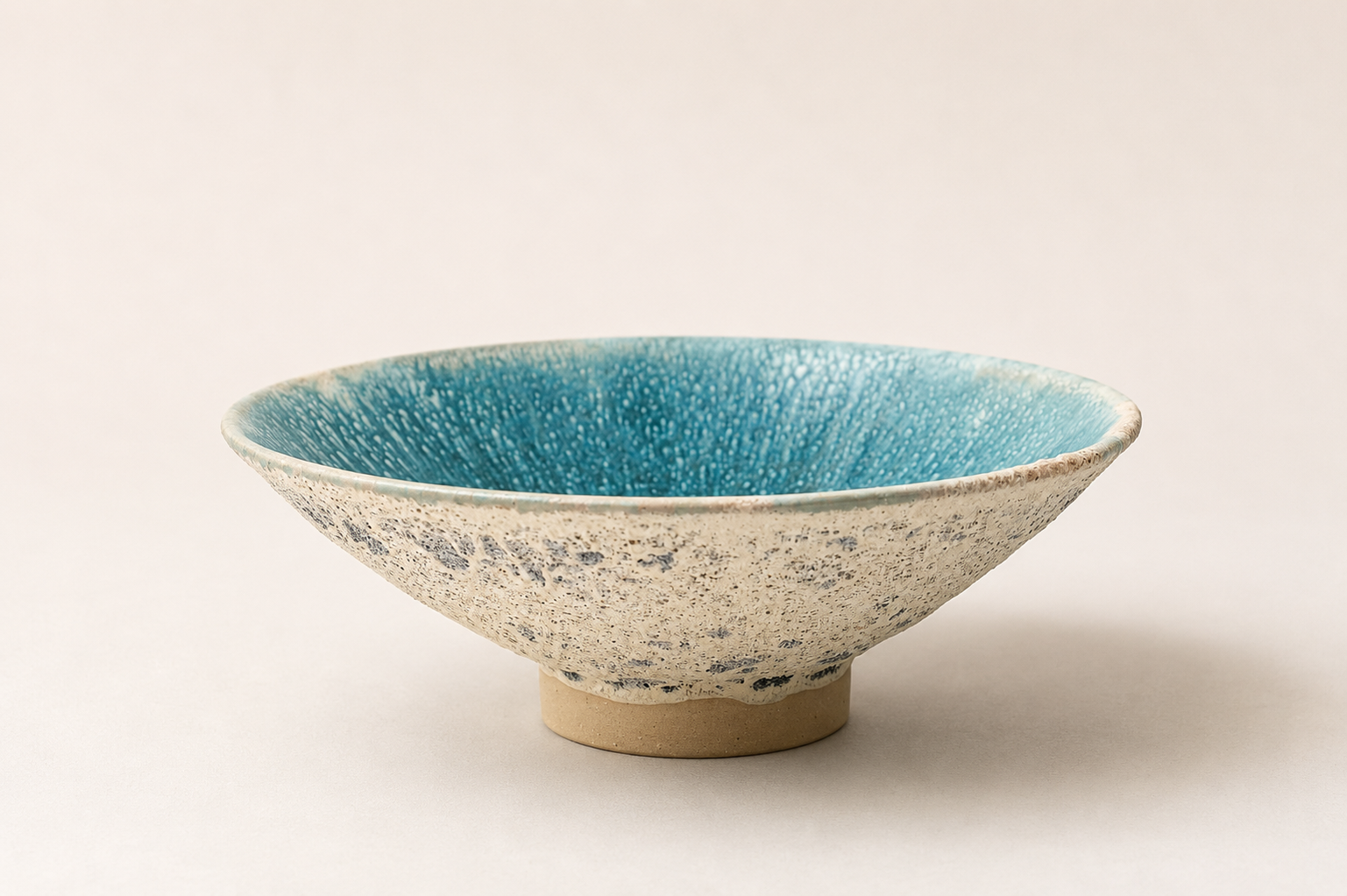 Wide V-shaped vessel with a turquoise interior and pale textured exterior