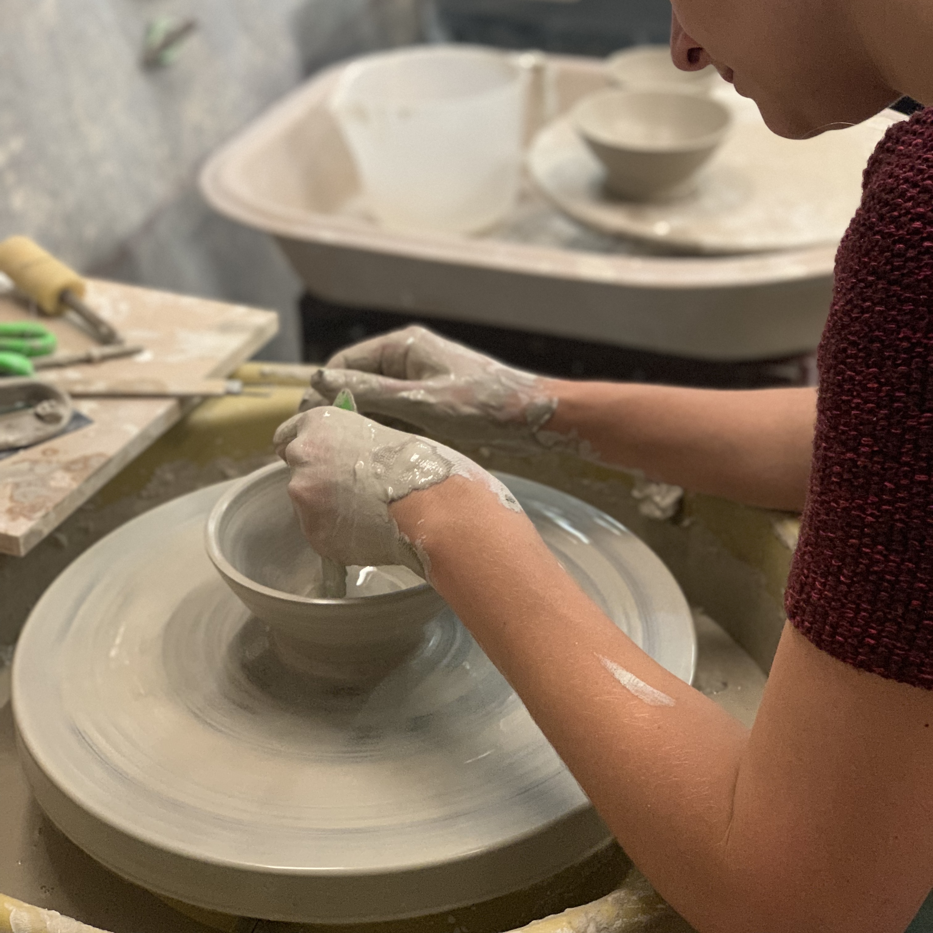 A student learning to throw clay on the pottery wheel